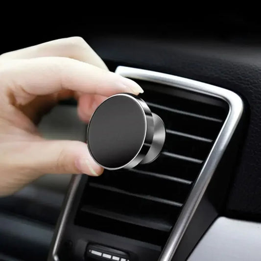 Hand placing a magnetic car mount onto a car's air vent.