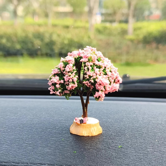 Small decorative tree with pink flowers on a car dashboard