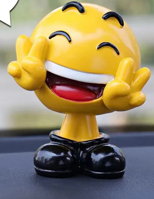 Yellow emoji figurine with black shoes on a car dashboard