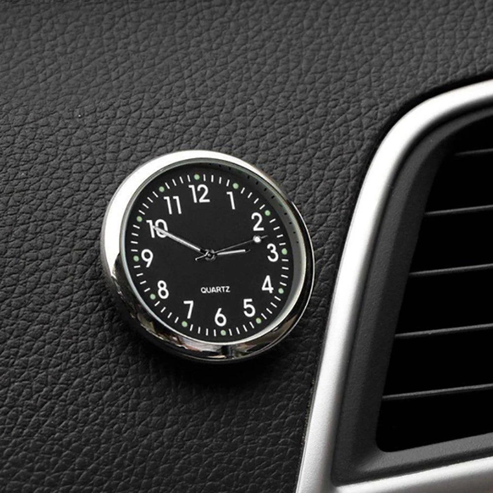 Car clock with black face and silver casing on a car dashboard
