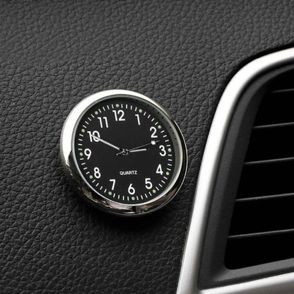 Car clock with black face and silver casing on a vehicle dashboard