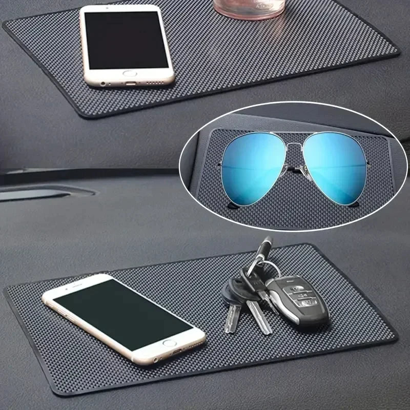 Car dashboard with a black mat holding a phone, keys, and sunglasses.