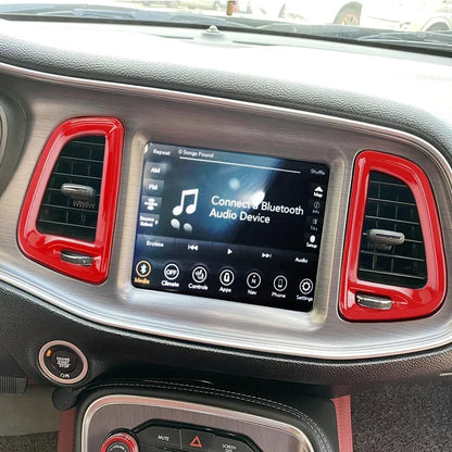 Car dashboard with a touchscreen display and red air vent frames.