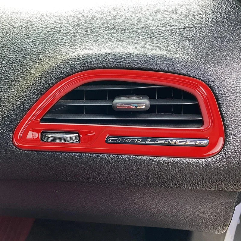 Car interior with a red 'Challenger' air vent cover on a gray dashboard.