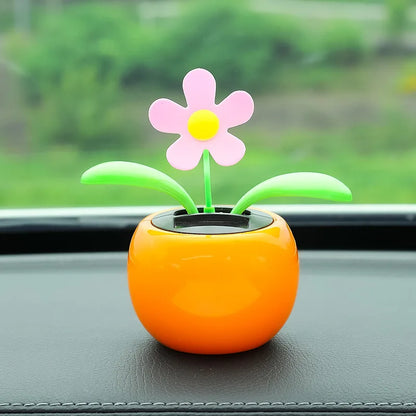 Colorful flower-shaped toy on a car dashboard with a blurred green outdoor background