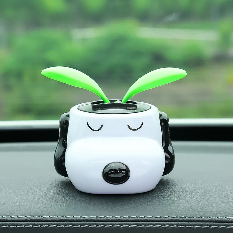 Cute white and black device with green antenna on a car dashboard
