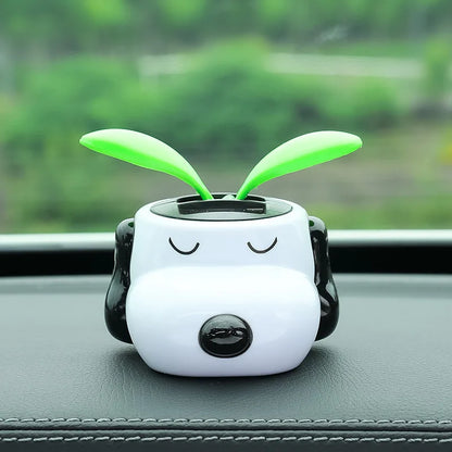 Cute white and black device with green antenna on a car dashboard