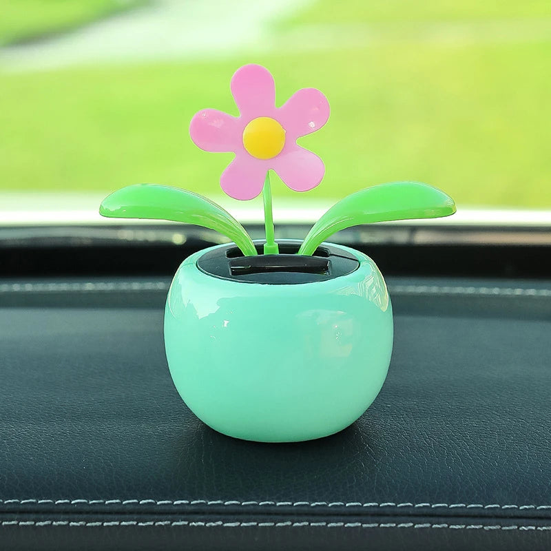 Decorative flower in a pot on a car dashboard with a blurred green background