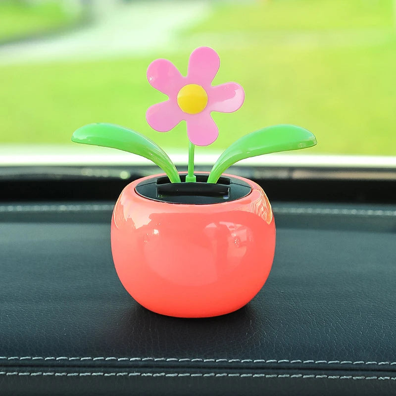 Decorative flower pot with a pink flower on a car dashboard
