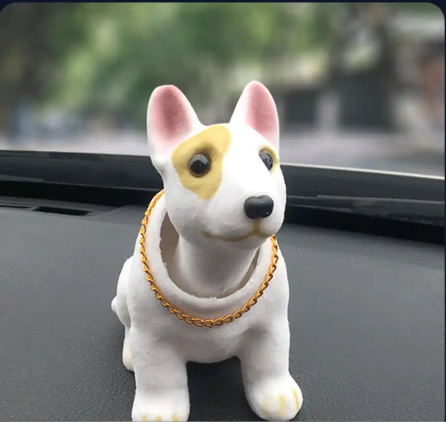 Dog figurine with a gold chain on a car dashboard