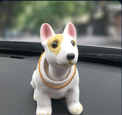 Dog figurine with a gold chain on a car dashboard