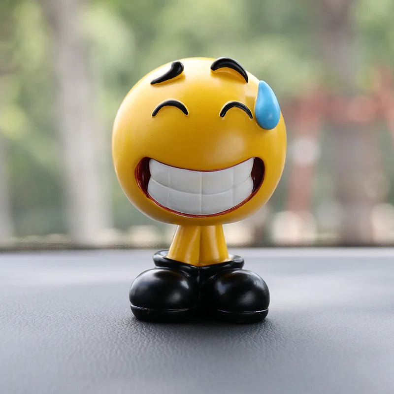 Emoticon figurine with a laughing expression on a car dashboard