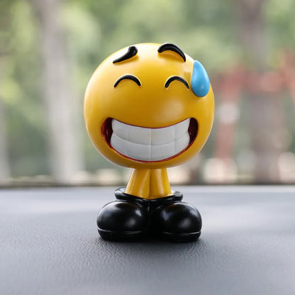 Emoticon figurine with a laughing expression on a car dashboard