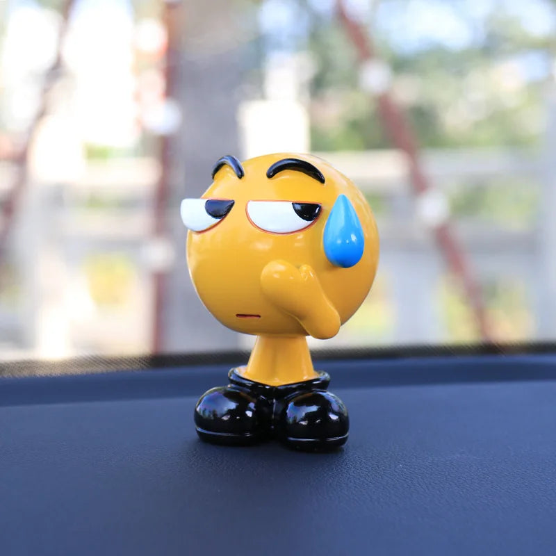 Emoticon figurine with a sad expression on a car dashboard