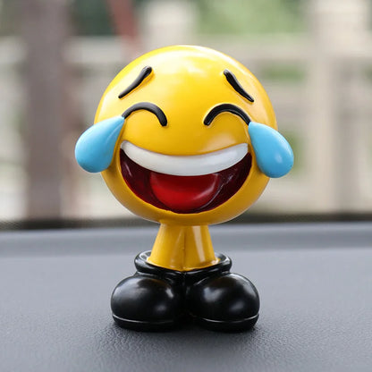 Emoticon figurine with tears of joy on a car dashboard