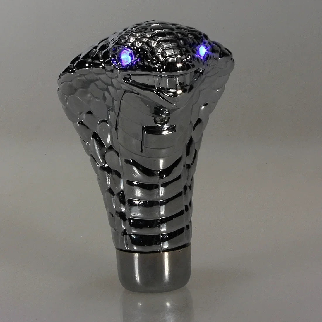 Metallic car shift knob with snake design on a gray background