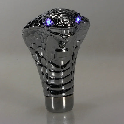 Metallic car shift knob with snake design on a gray background