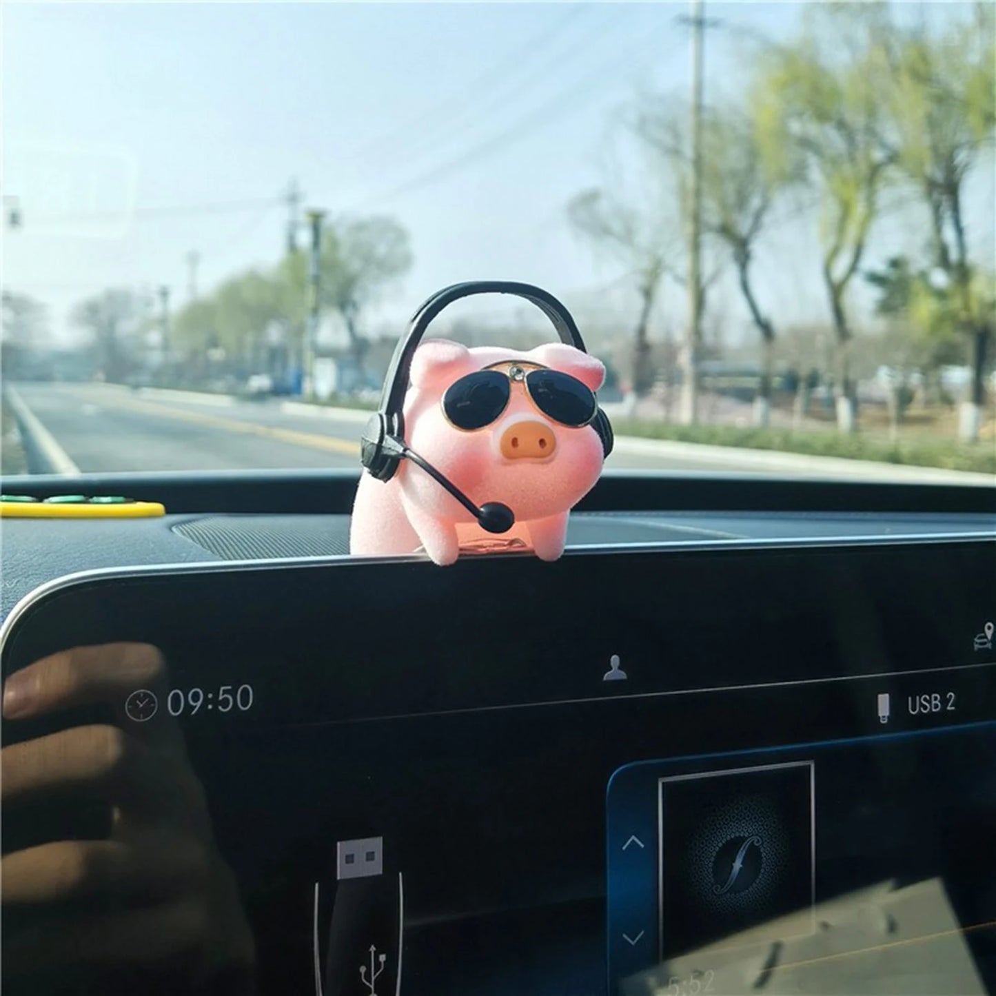 Pink piggy bank with sunglasses and a headset on a car dashboard