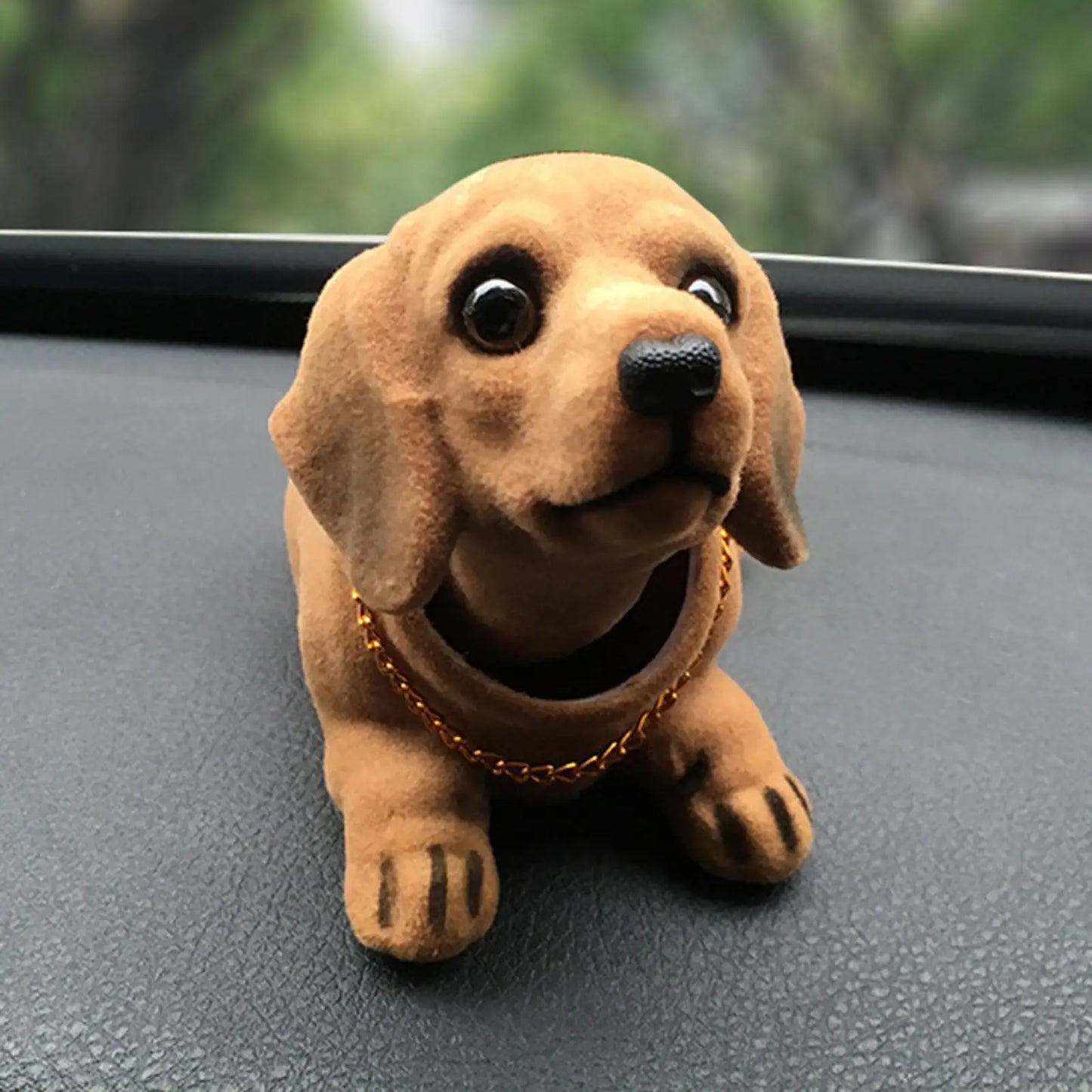 Plush dog toy on a car dashboard with a blurred green background