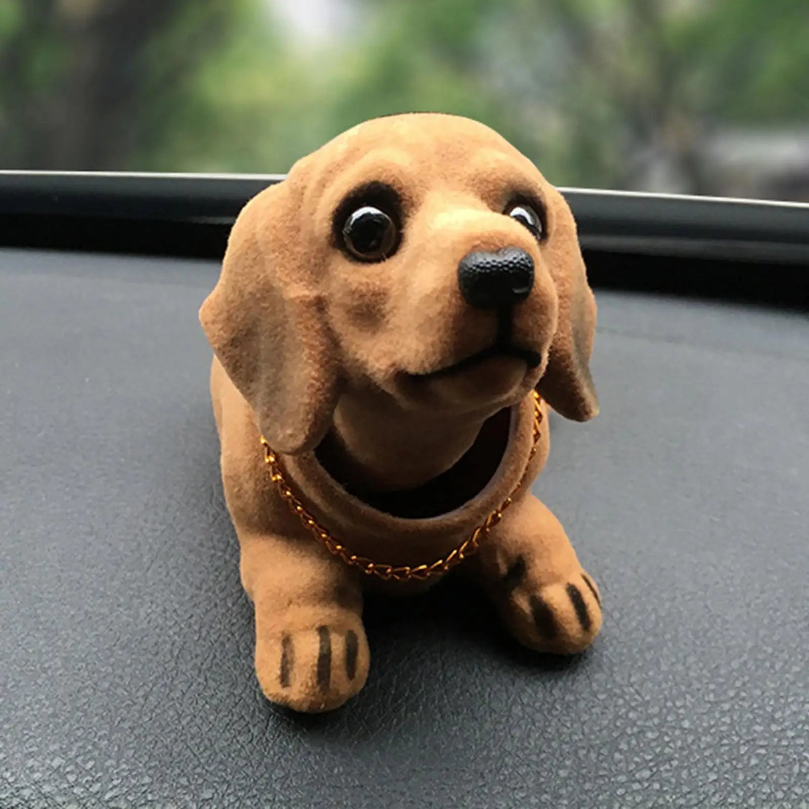Plush dog toy on a car dashboard with a blurred green background