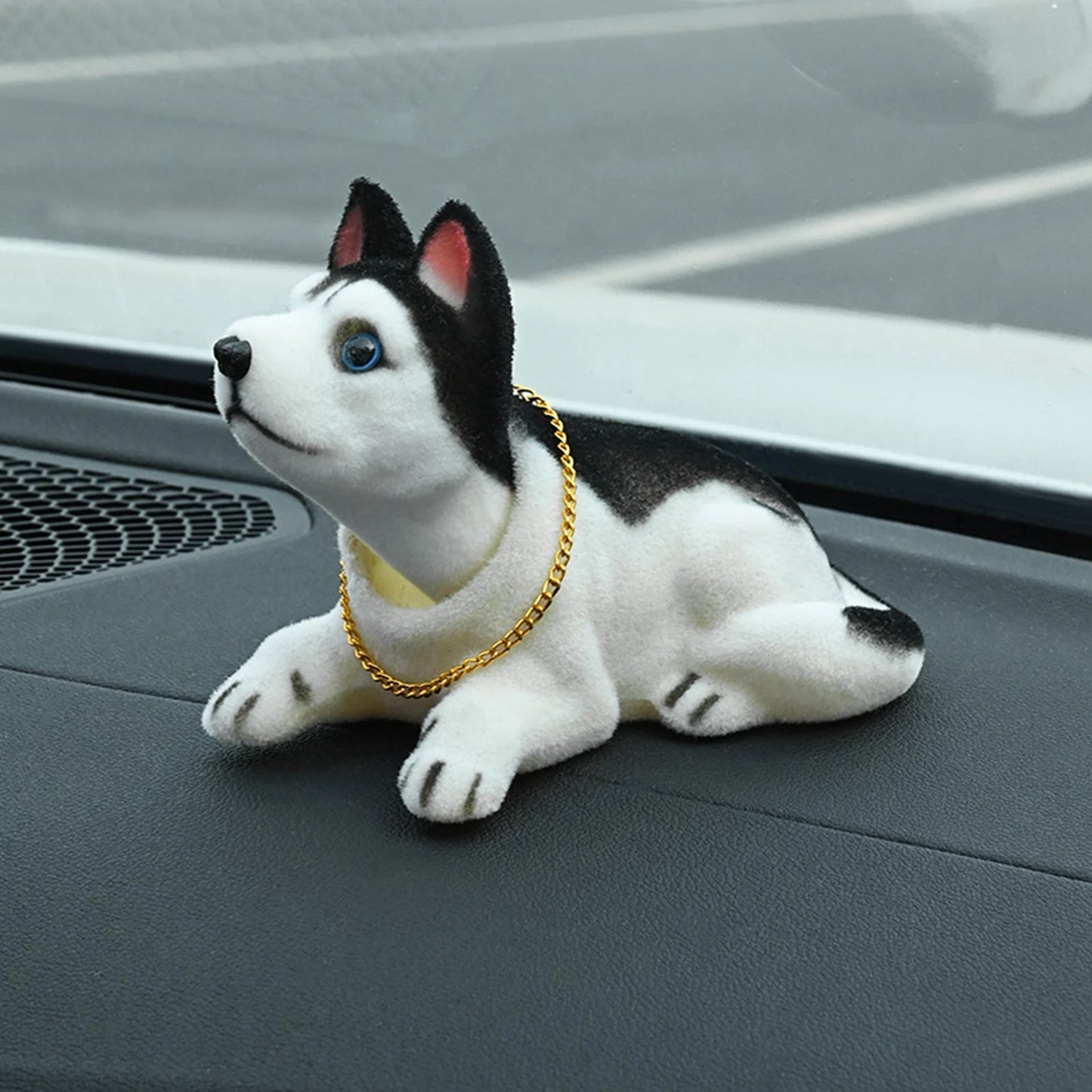 Plush dog toy with a gold chain on a car dashboard