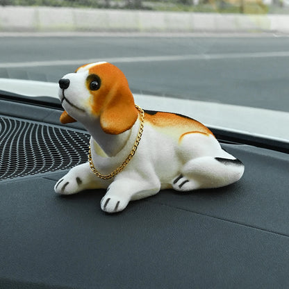 Plush dog toy with a gold chain on a vehicle dashboard