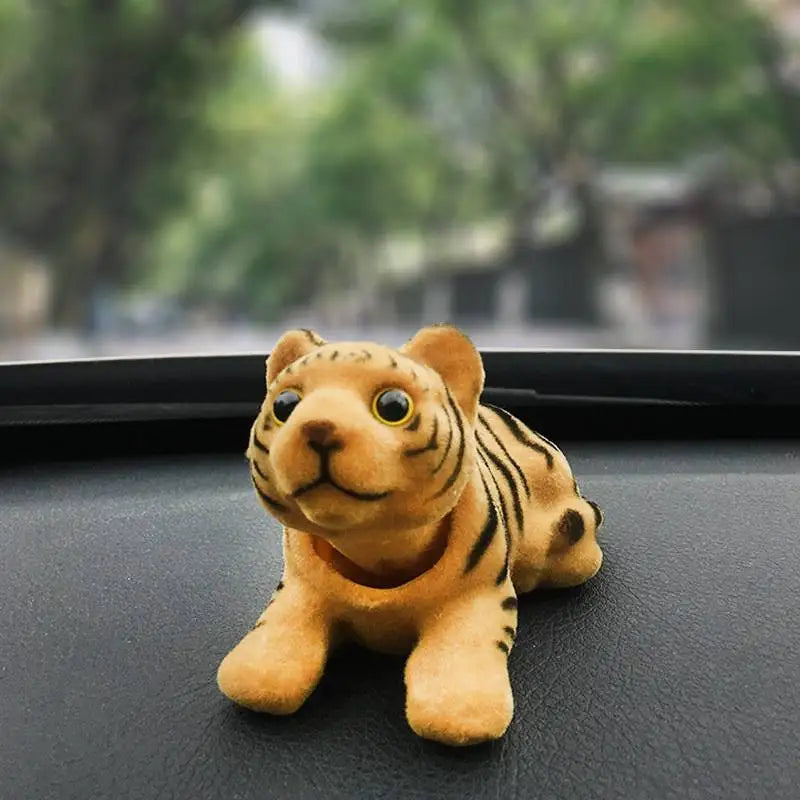 Plush tiger toy on a car dashboard with a blurred outdoor background