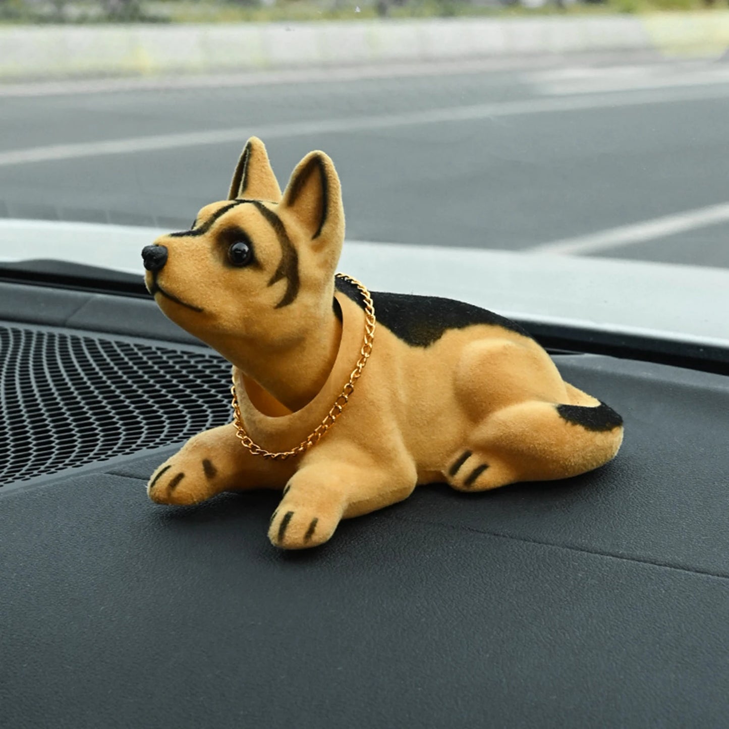 Plush toy dog with a gold chain on a car dashboard
