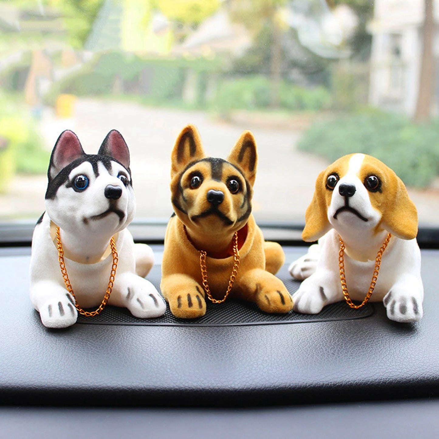 Three dog figurines with chains on a car dashboard