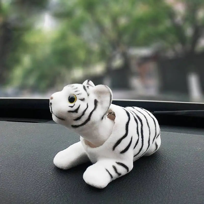 White tiger figurine on a car dashboard with a blurred outdoor background
