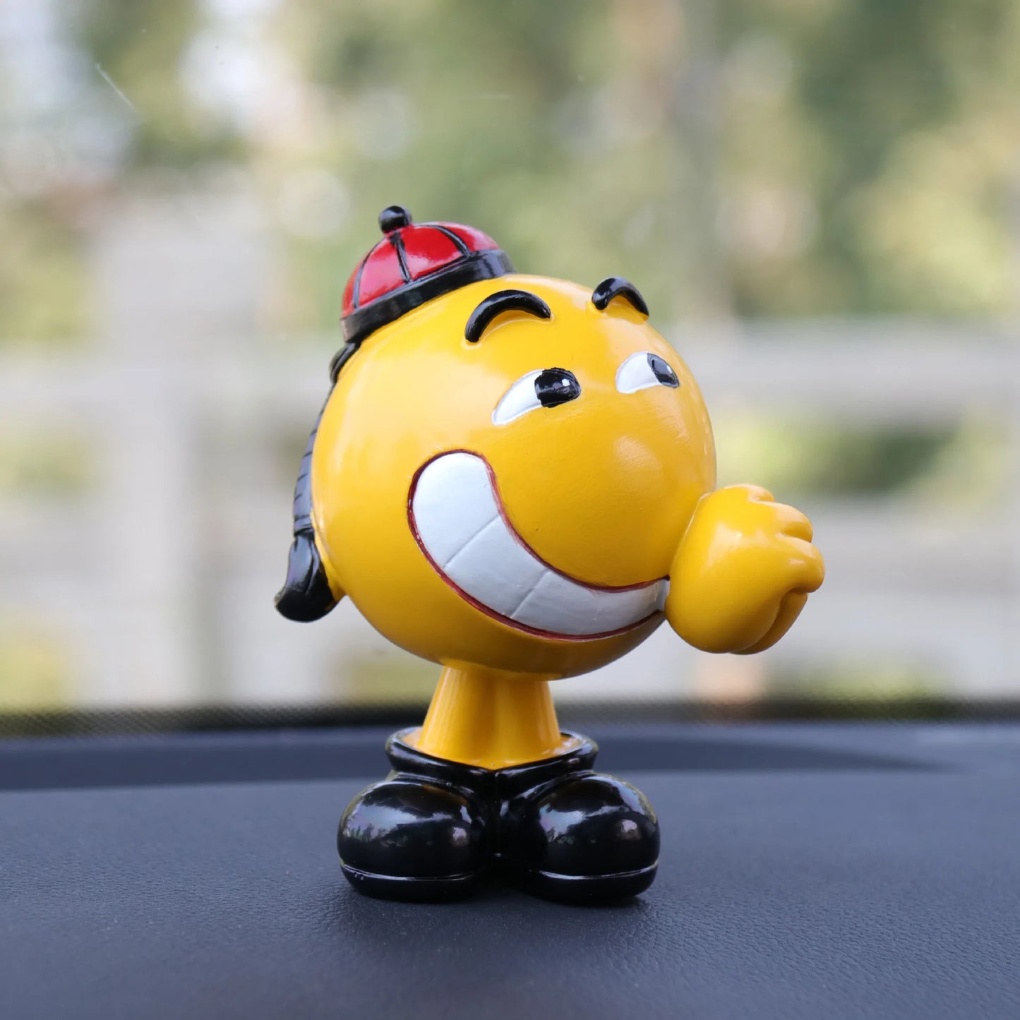 Yellow cartoon character figurine with a red hat on a car dashboard