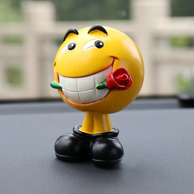 Yellow emoji figurine with a rose on a car dashboard