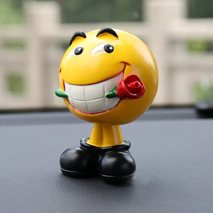 Yellow emoji figurine with a rose on a car dashboard