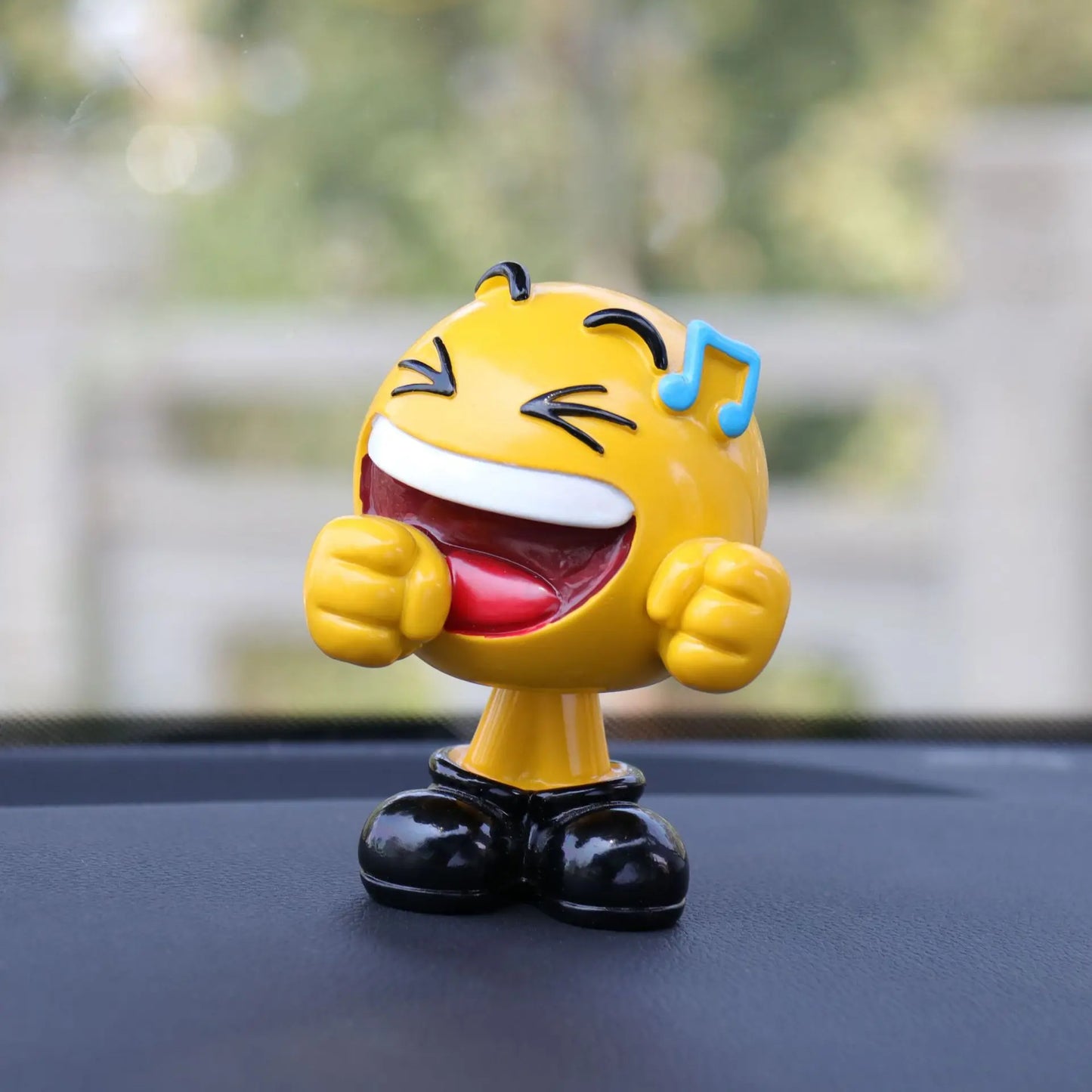 Yellow emoji figurine with musical notes on a car dashboard