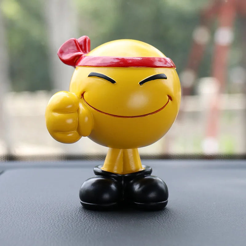 Yellow smiley face figurine with a red bandana on a car dashboard